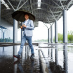 Handsome redhaired businessman with umbrella drinking coffee