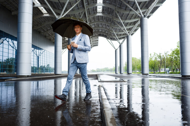 Handsome redhaired businessman with umbrella drinking coffee
